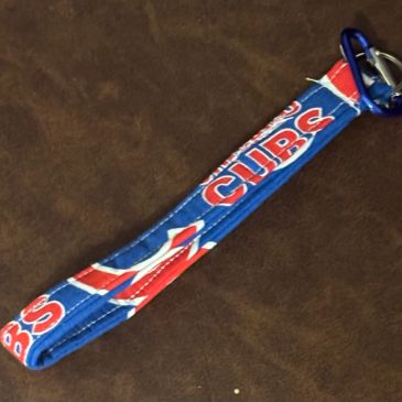 Blue Cubs wristband with carabiner on brown surface.