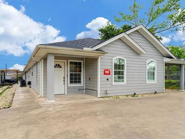 Single-story gray house with white trim and a concrete driveway under a blue sky.