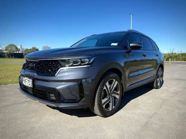 A sleek dark gray Kia SUV parked on a sunny day with a clear blue sky.