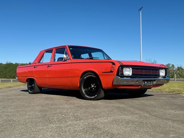 Classic bright orange vintage car parked on a sunny day.