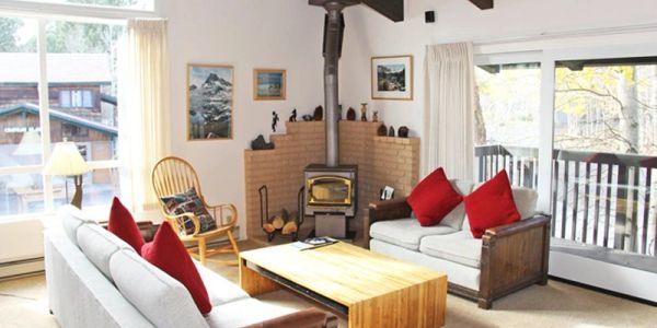 Cozy living room with wood stove and red pillows.
