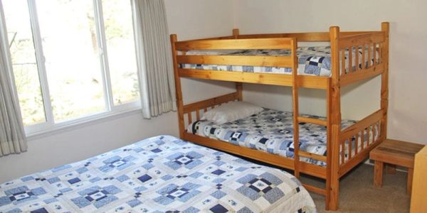 Room with bunk beds and a double bed with blue bedding.