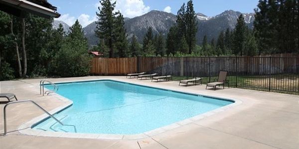 Outdoor swimming pool with mountain views and lounge chairs.