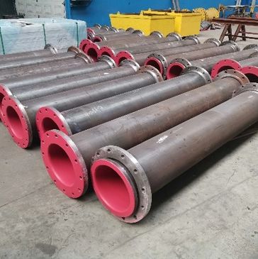 Large industrial pipes with red flanges on a factory floor.