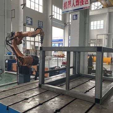 Robot arm welding metal frame in workshop.