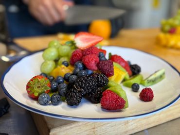 Fresh mixed berries and fruits on a white plate.