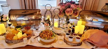 Elegant buffet setup with flowers, candles, and salad dressings.