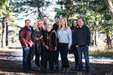A multi-generational family stands together outdoors in winter scenery.