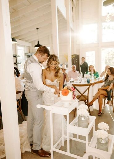 Bride and groom cutting their wedding cake in a sunlit room.