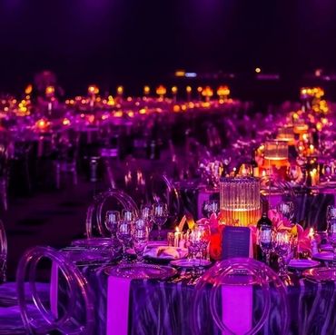 Elegant banquet tables with purple lighting and glowing candles.