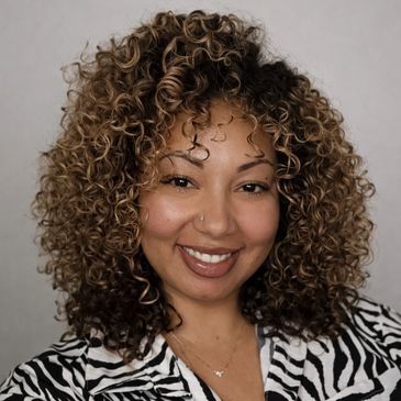 Smiling woman with curly hair in a zebra-patterned top.