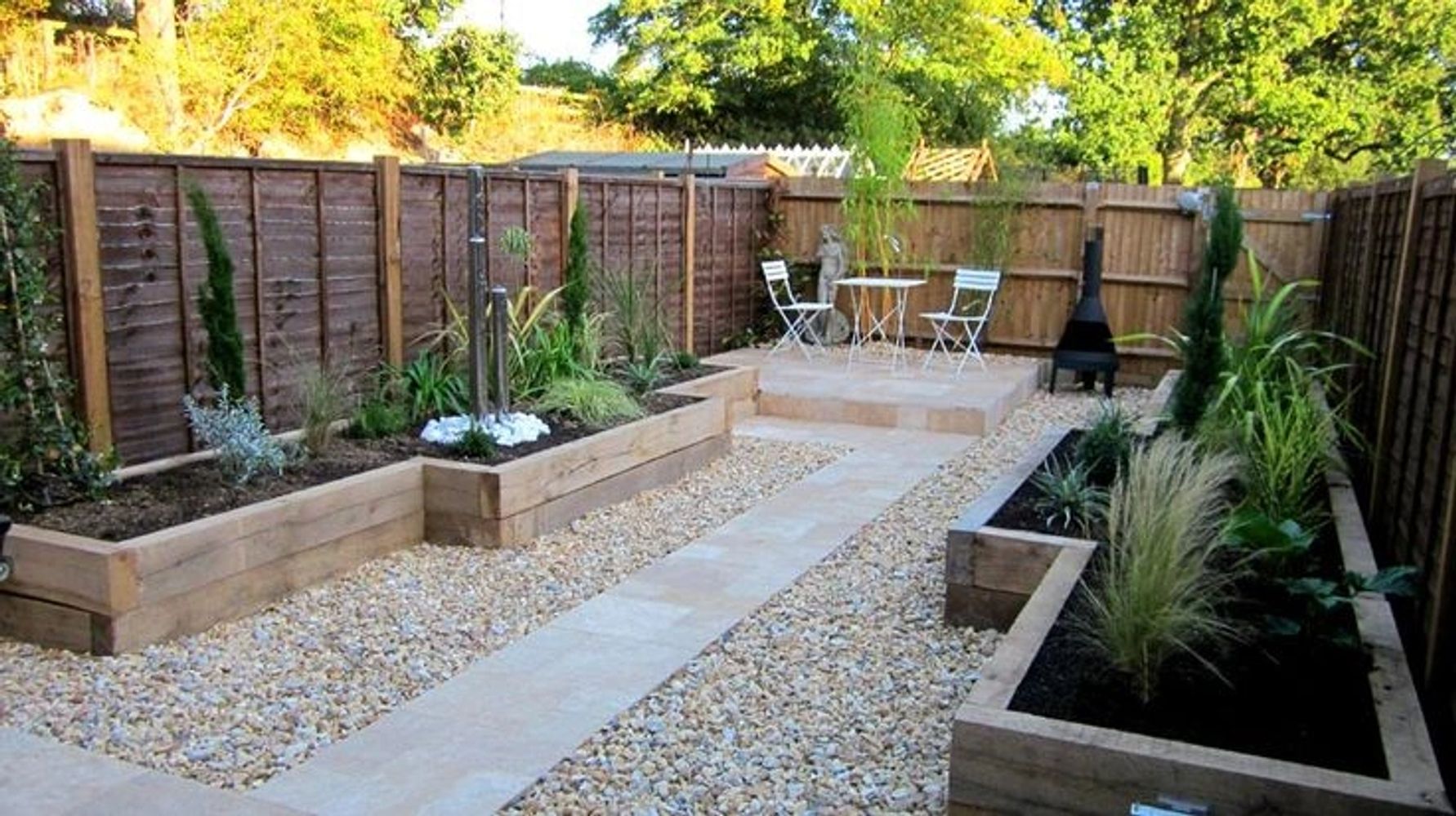 Neatly landscaped garden with raised wooden flower beds and a stone path.