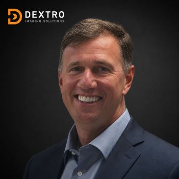Smiling man in a suit with Dextro Imaging Solutions logo.