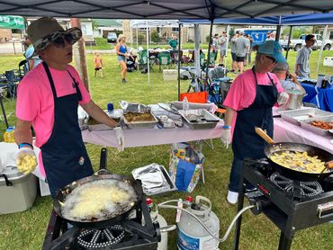 Octane employees in pink shirts with black aprons frying food to serve