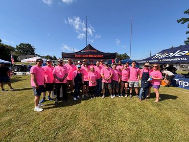Octane employees in pink shirts in front of the company EZ UP