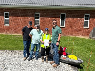 Four people standing in front of a brick building outside