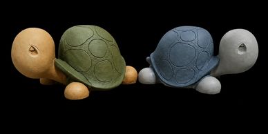 Four colorful turtle sculptures with simple, rounded shapes on a black background.