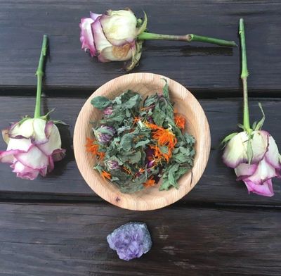 Roses representing divine feminine energy and a bowl of herbs for a yoni steam ritual