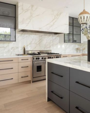Modern kitchen with marble countertops and two-tone cabinetry.