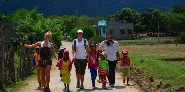Group of women and children joyfully walking on a rural path.