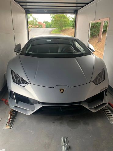 Silver Lamborghini sports car inside a transport truck.
