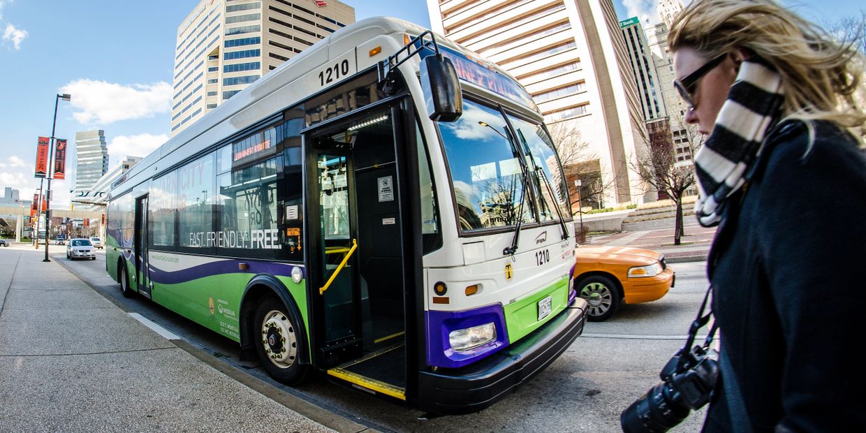 City bus with open doors waiting at a downtown stop on a clear day.