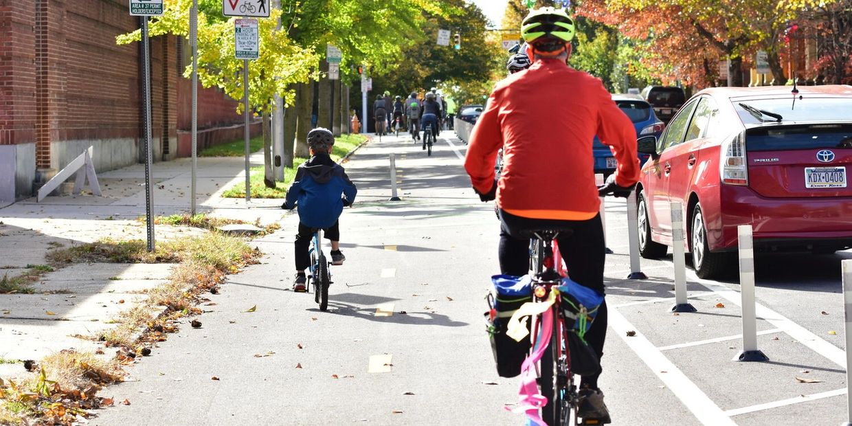 People biking on a sunny autumn day in a city bike lane.