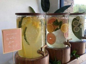 Three glass water dispensers with infused fruits and herbs.