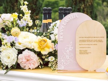 Elegant floral arrangement with champagne bottles and an Easter-themed sign.