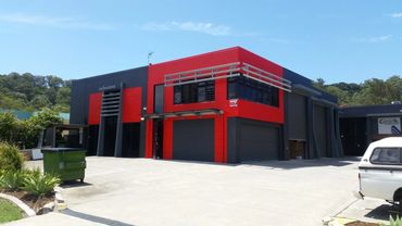 Modern red and black industrial building with clear sky.