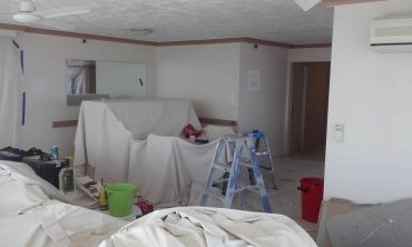 Room undergoing renovation with covered furniture and ladders.