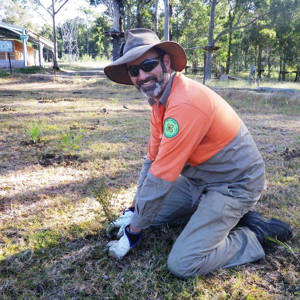 Man planting a young tree in a field.