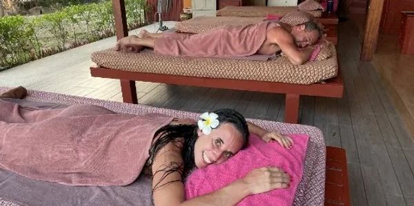 Two people relaxing on massage tables, wrapped in towels at a spa.