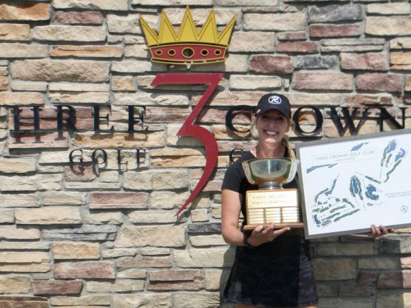 Smiling woman holding a trophy and map at Three Crowns Golf Club.