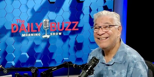 Man smiling on a morning show podcast set.
