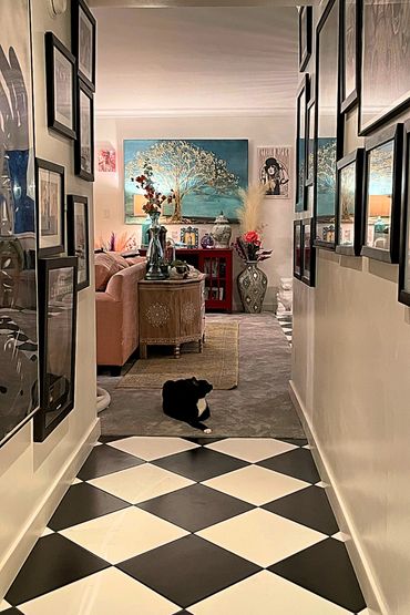 A cat at the end of a hallway with a checkerboard floor in a maximalist room.