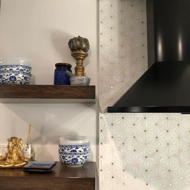 Close up of black stove hood, custom wood shelving, and blue and gold bowls and accents