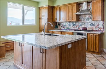 Tropical kitchen with green walls, large island, and sunshine coming through the window.