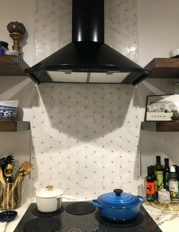 Gold marble backsplash, black stove hood, induction cooktop, le creuset cast iron cookware