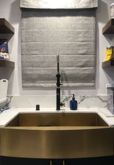 Gold farm sink with gray roman shades