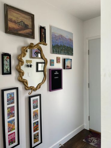 Gallery wall with gold snake mirror, oil painting, Mexican tiles, Disney art, mst3k art