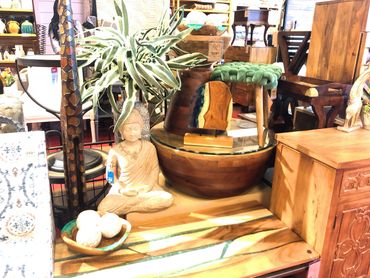 Retail display with a large garden Buddha statue, mango wood tables, and resin decor