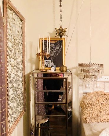 A mirrored jewelry armoire with a candelabra and moroccan lamp, chandelier, and vintage candelabra.
