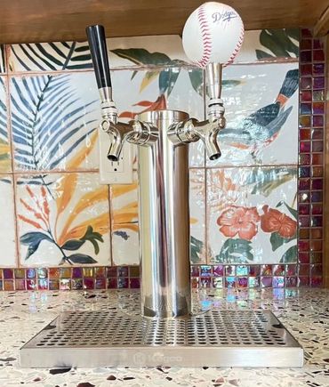 A custom countertop beer tap with a baseball handle and a mosaic backsplash.