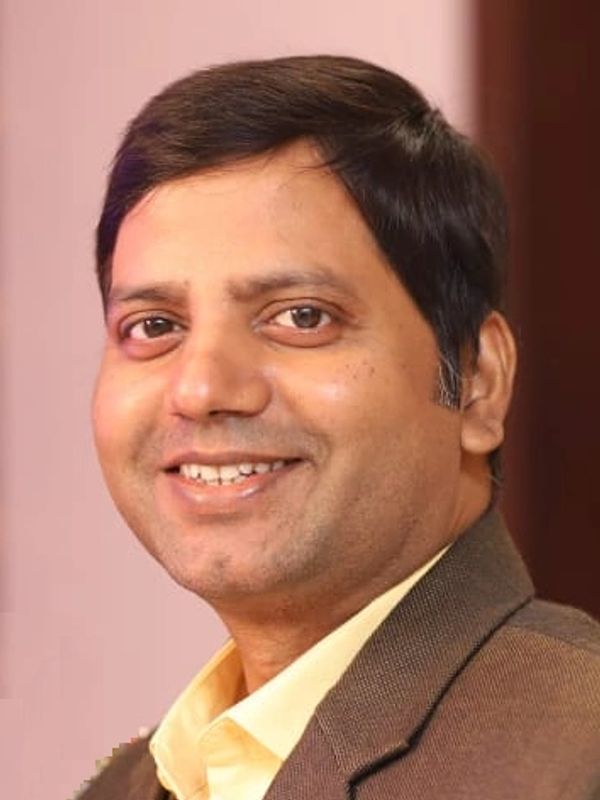 Smiling man in a brown suit jacket.