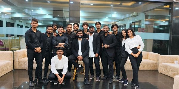 Group of young adults posing indoors in formal black and white attire.