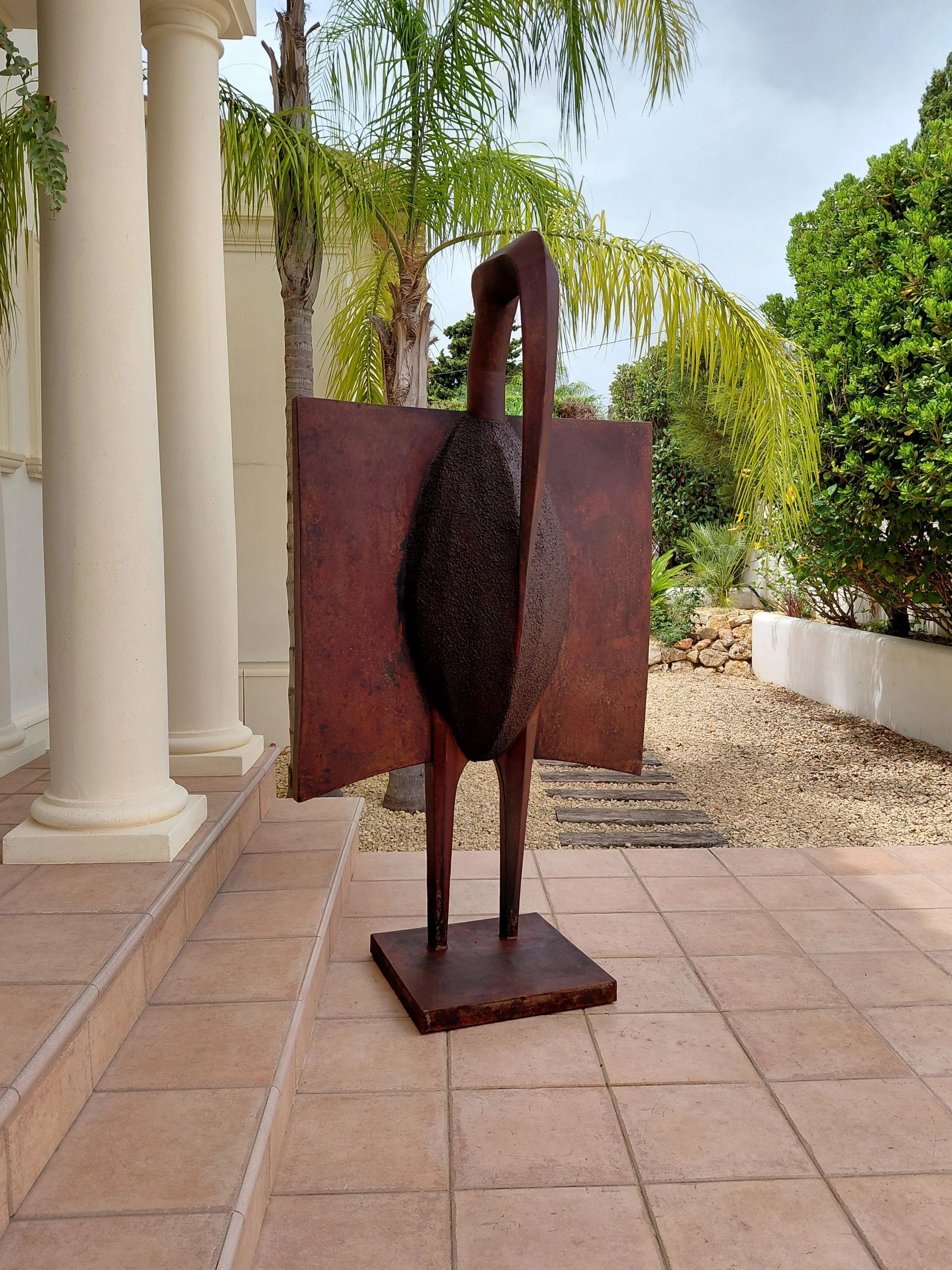 Abstract rust-colored metal sculpture outdoors.