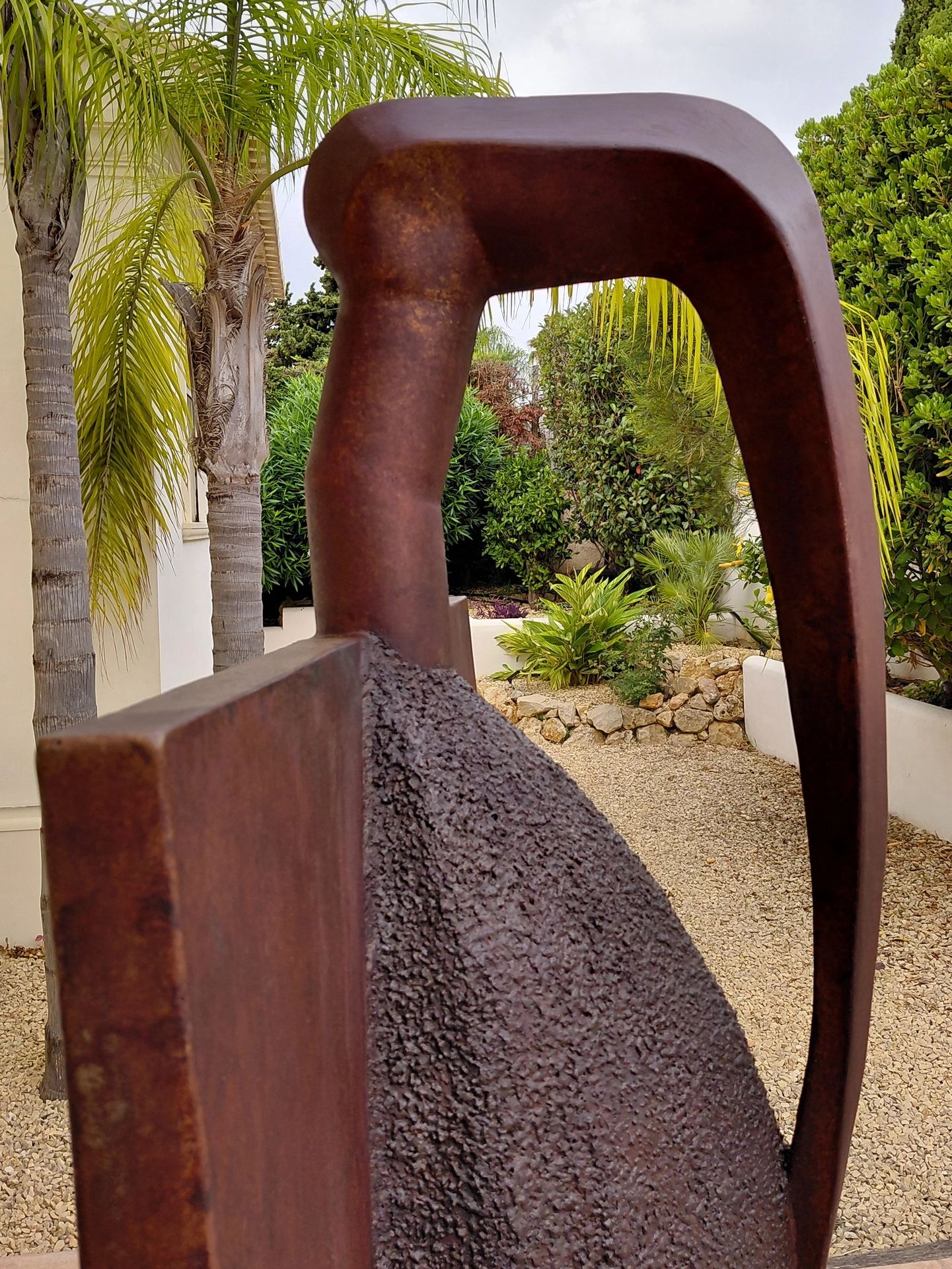 Rustic abstract metal sculpture in a garden setting.