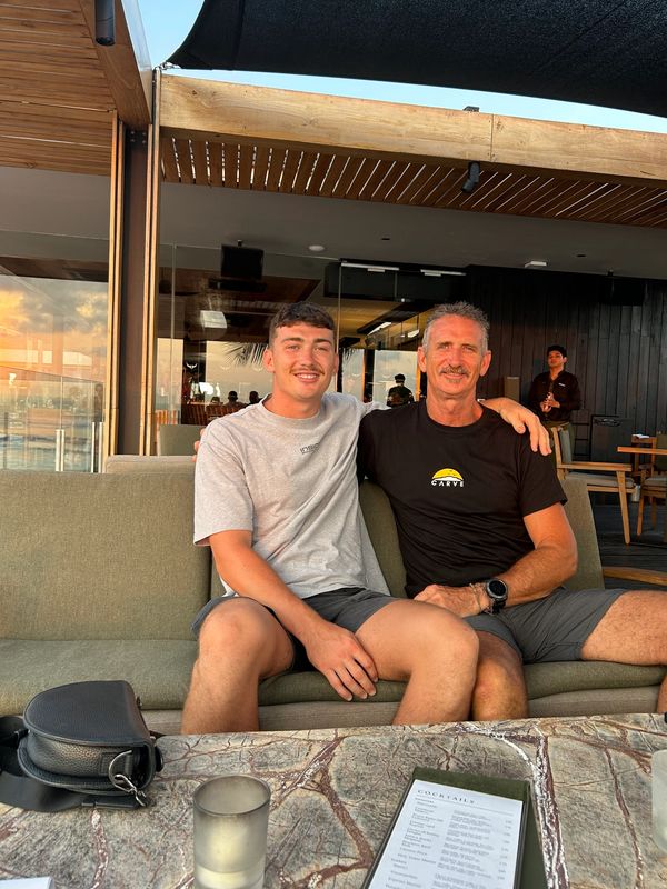 Two men sitting together on a couch smiling.