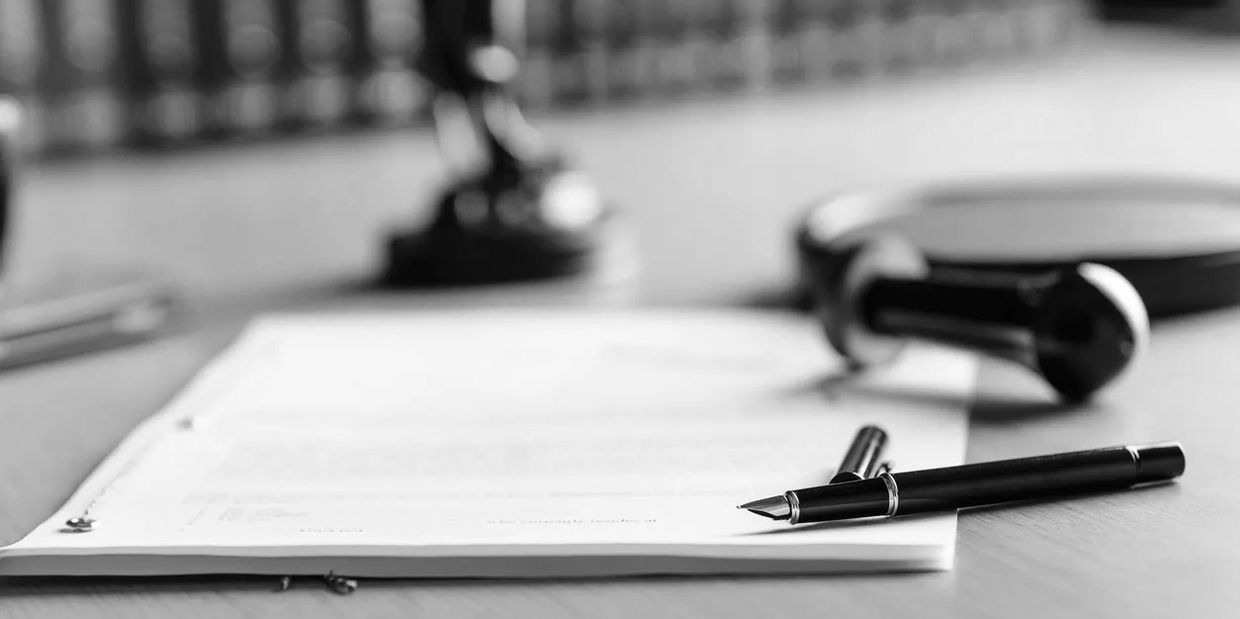 Black fountain pen resting on a legal document on a wooden desk.